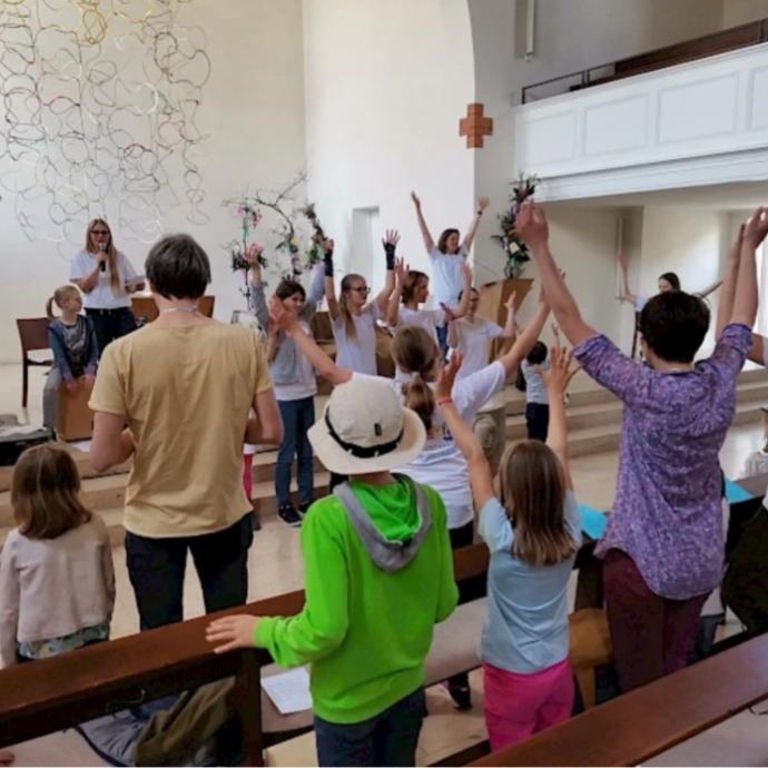 Familien singen mit einer Musikgruppe in einem Gottesdienstraum