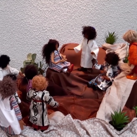 Biblische Erzählfiguren scharen sich um Jesus am Berg und hören ihm zu.