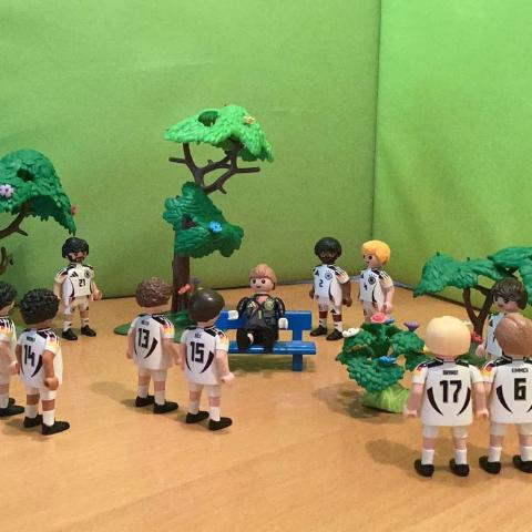 Playmobilmännchen als Fussballmannschaft gekleidet stehen immer zu zweit zusammen.