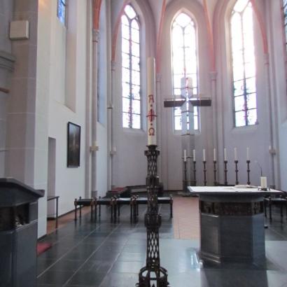 Altar mit Osterkerze und Blick in die Apsis mit durchbrochenem Kreuz