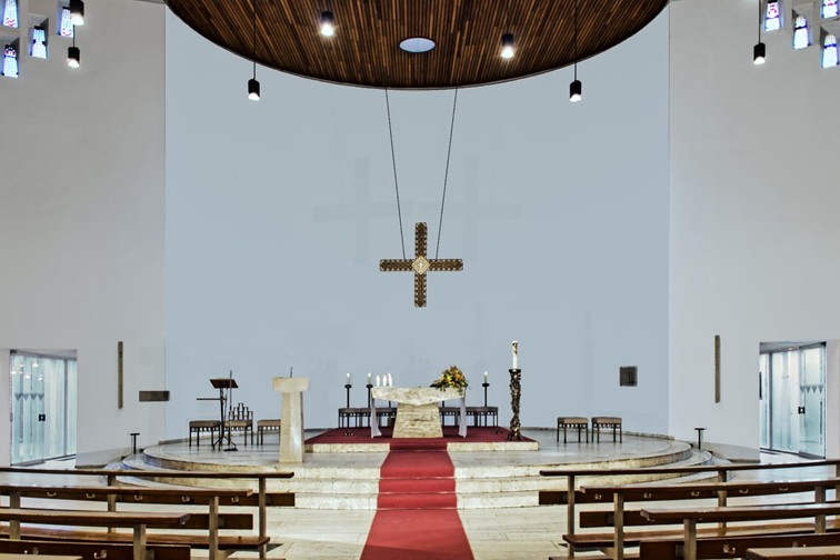 ein roter Teppich fürht von hinten nach vorne zum Altar mit Kreuz