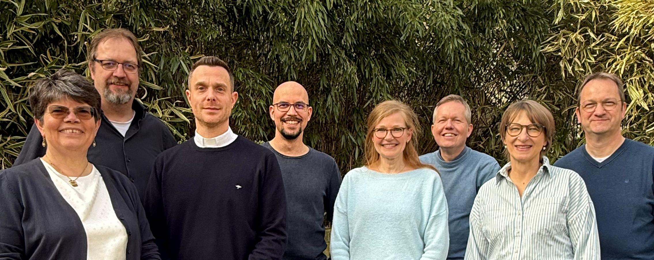 Drei Frauen und fünf Männer stehen in bunter Mischung beieinander.