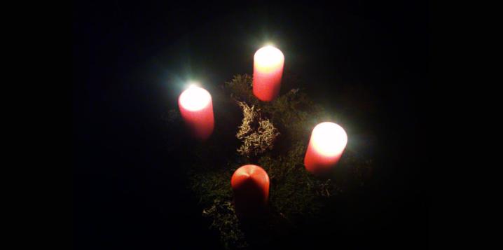 Drei von vier Adventkerzen leuchten in die Dunkelheit