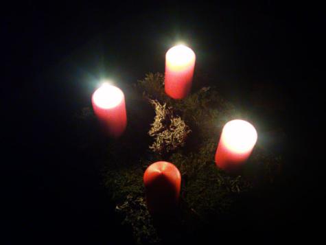 Drei von vier Adventkerzen leuchten in die Dunkelheit