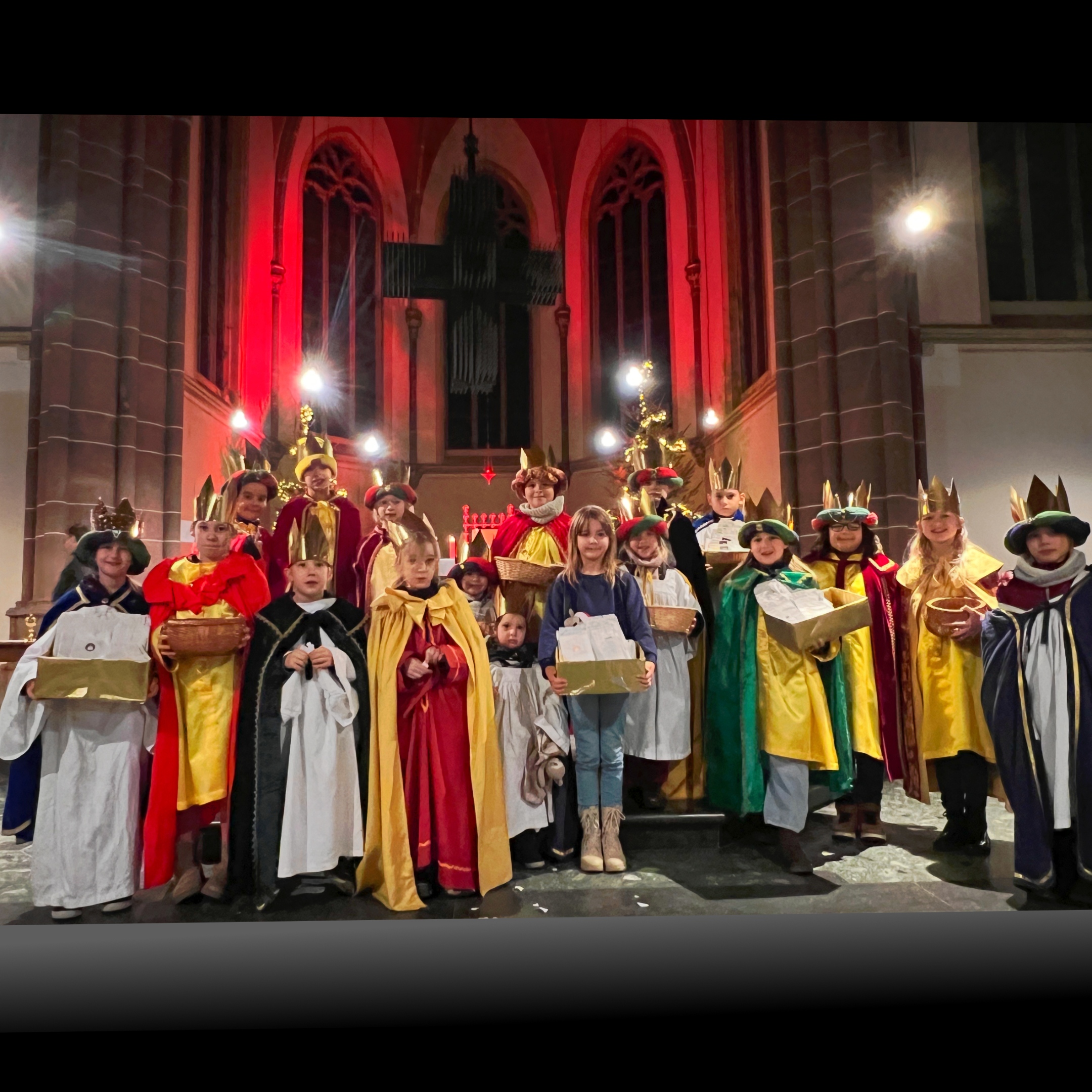 Kinder stehen als Sternsinger:innen in einer großen Gruppe auf den Stufen vor dem Altar der Schutzengelkirche